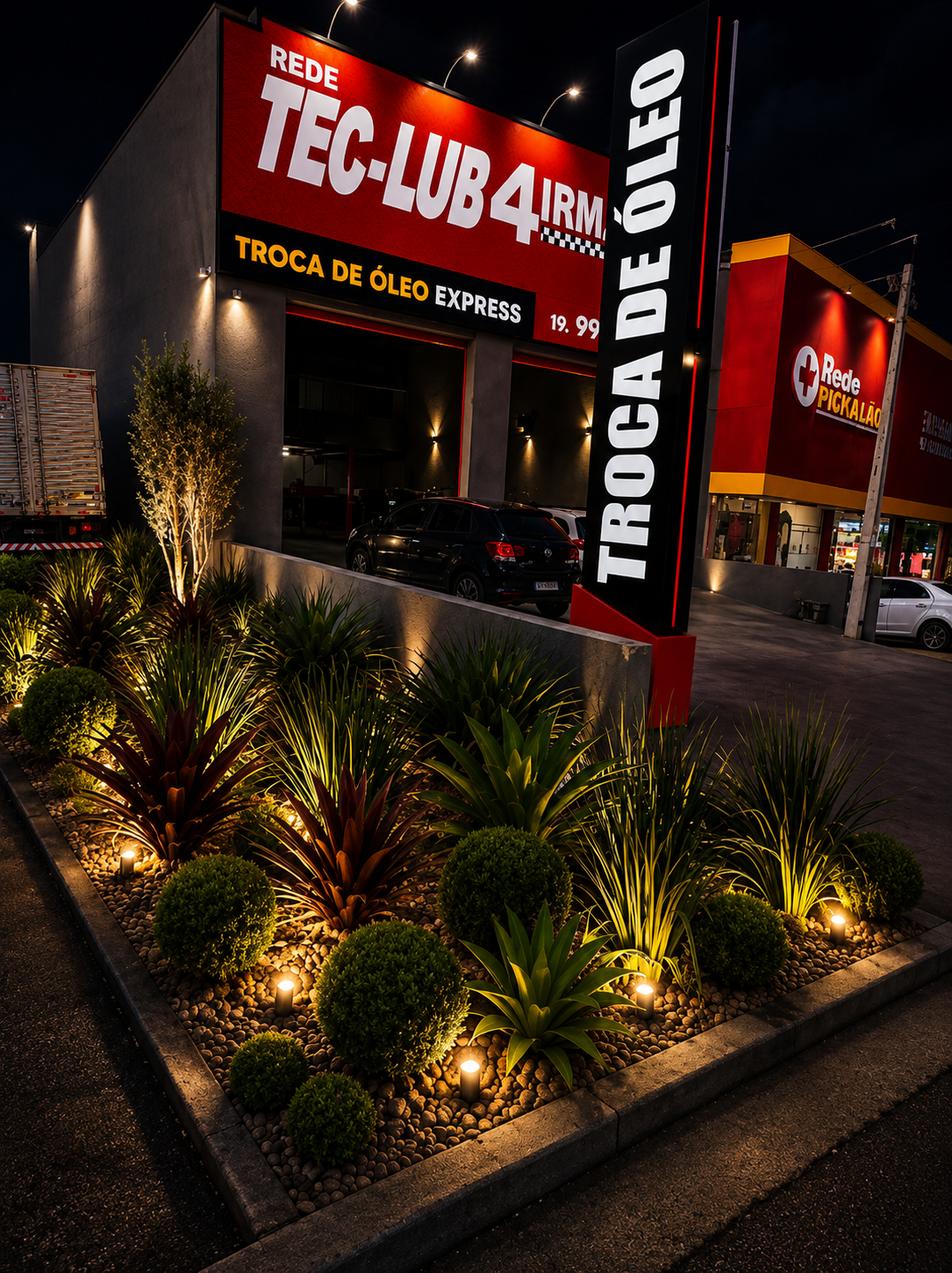 Fachada da TecLub Jaguariúna à noite com paisagismo iluminado na entrada